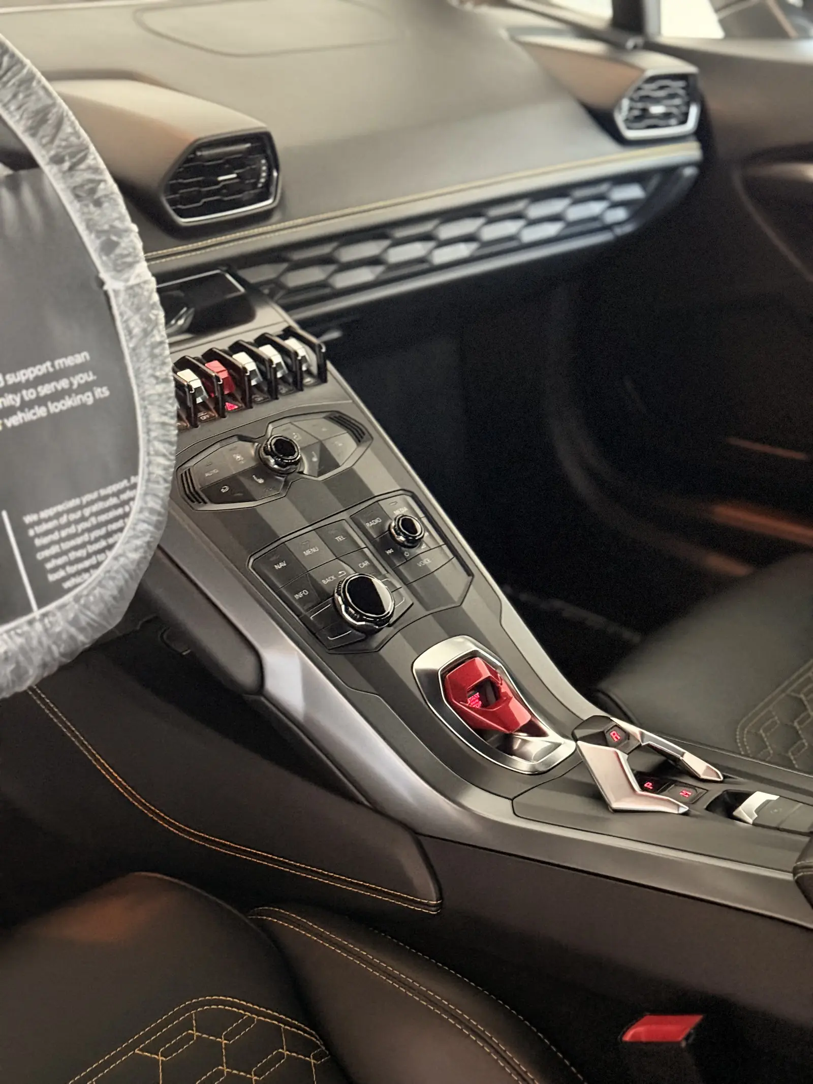 A Lamborghini Huracán interior after a detail, the steering wheel wrapped and a thank-you card tucked against it