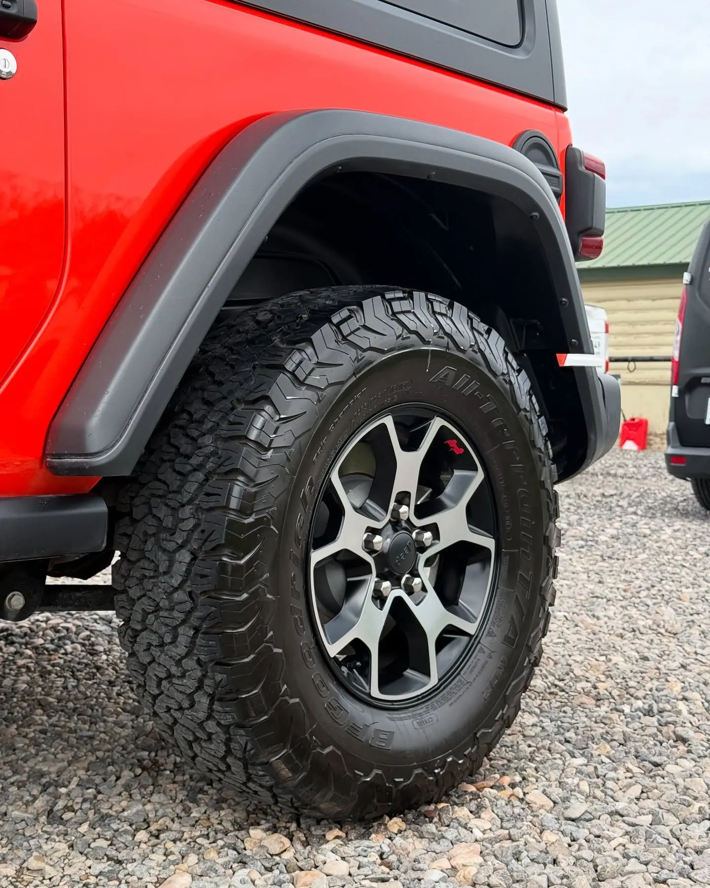 The rear fender and tire of a red Jeep Wrangler Rubicon after a detail