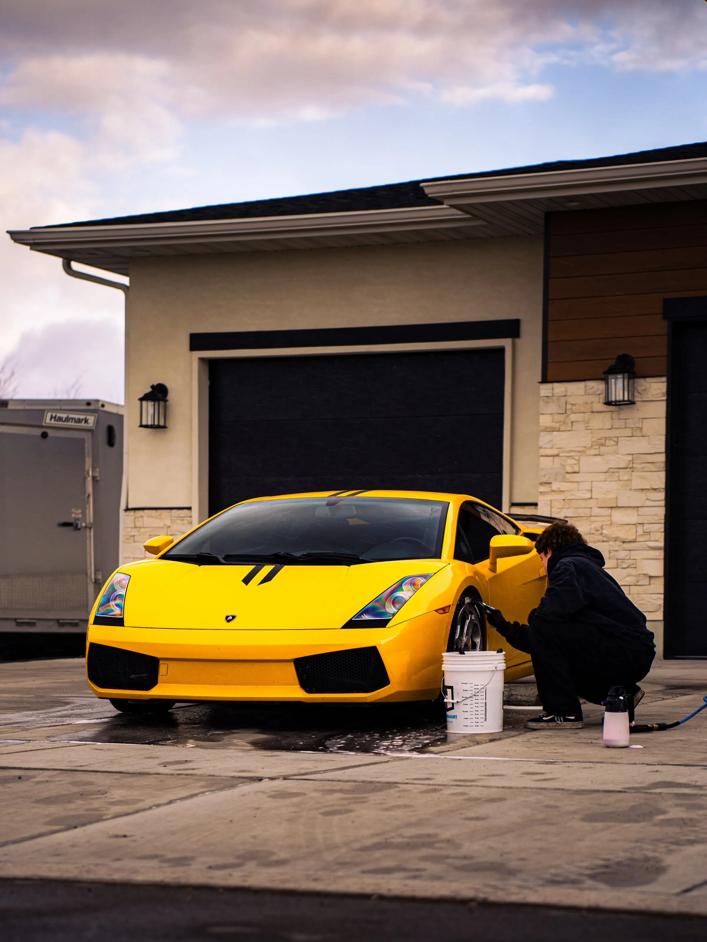 A yellow Lamborghini Gallardo being washed at a warm-lit garage door