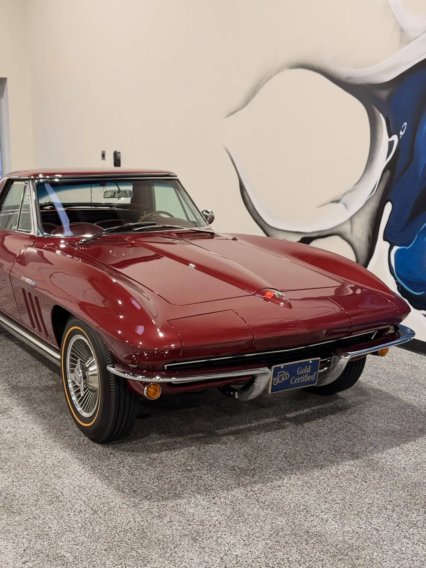 A maroon Corvette Stingray detailed against a painted mural