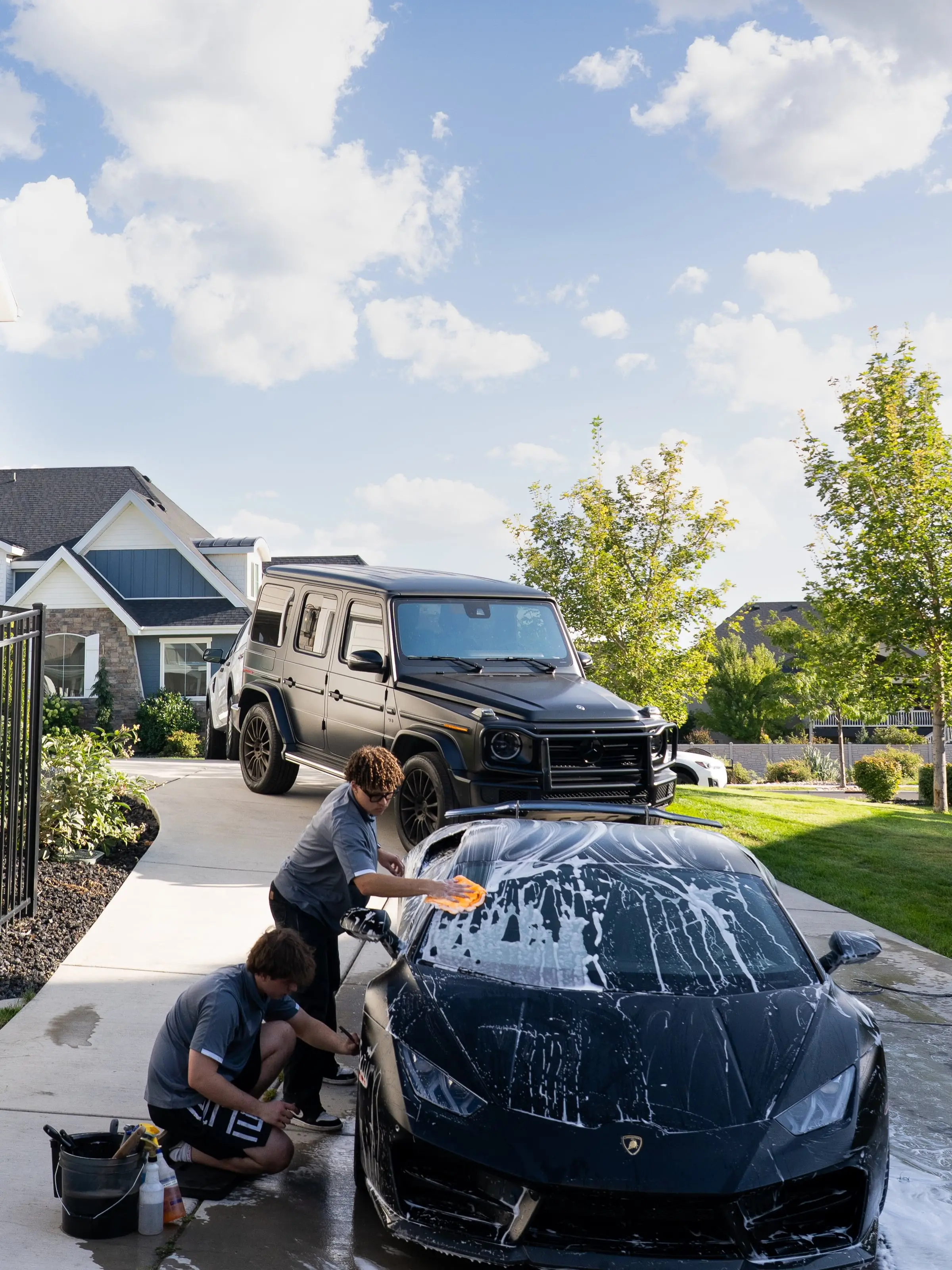 A black Lamborghini Huracan being foam washed in a client driveway