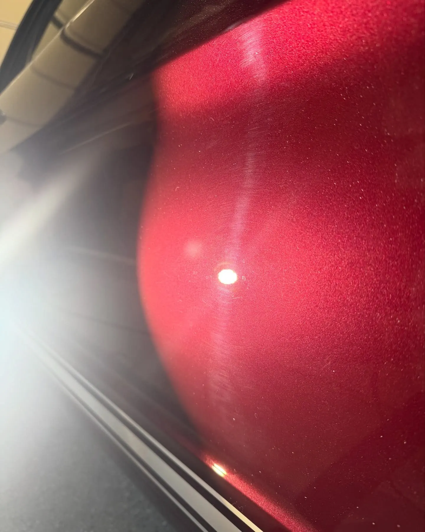 A single light bloom on the deep maroon body curve of the 1966 Mustang