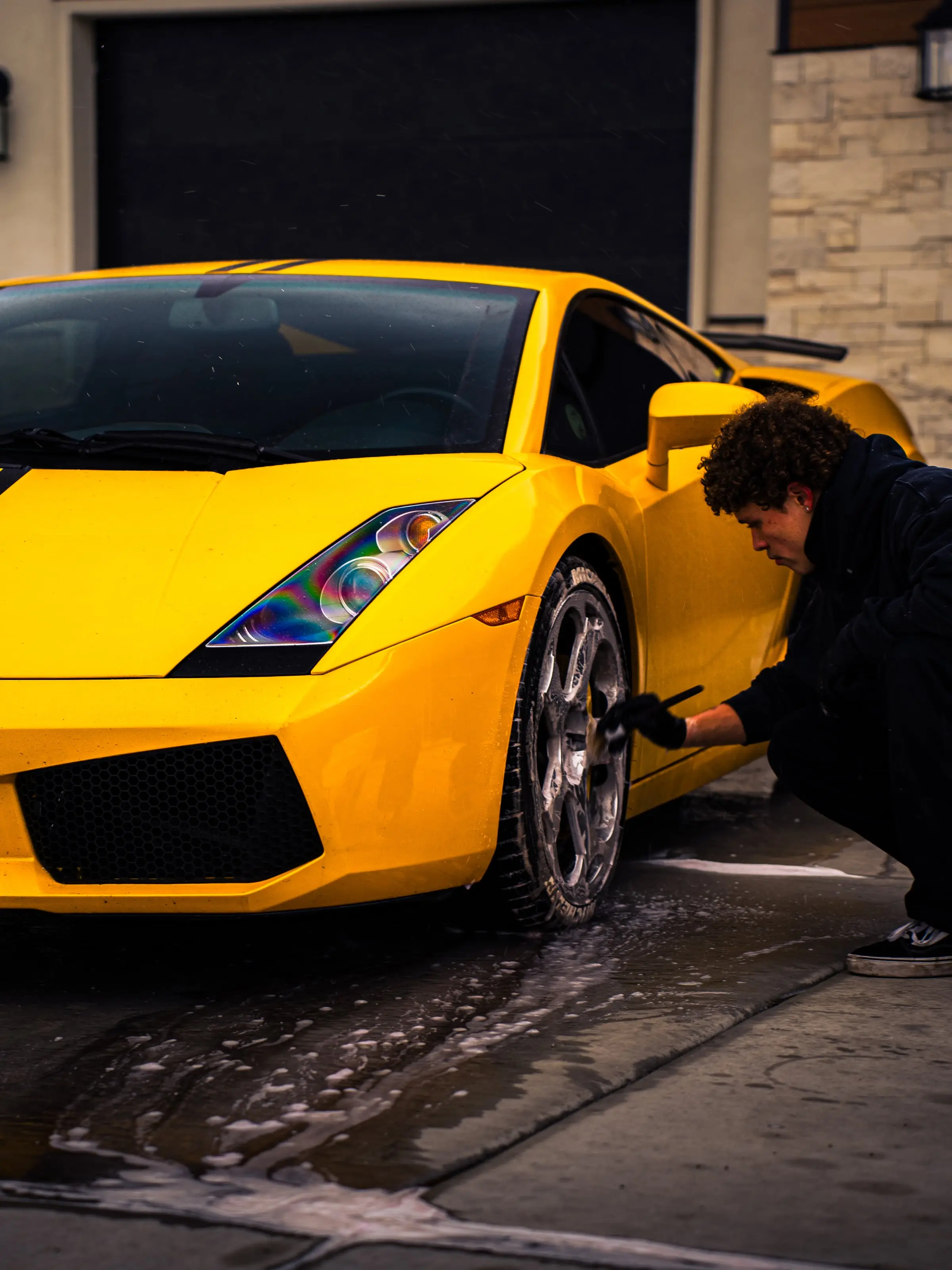 A yellow Lamborghini Gallardo being wiped down in a driveway