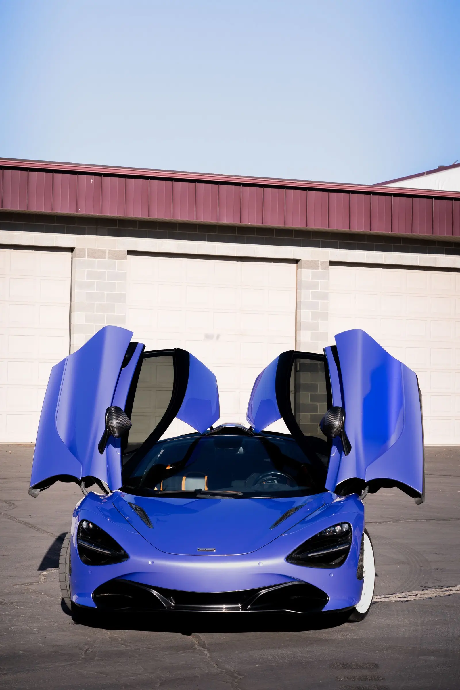A blue McLaren 720S with its doors up outside the detailing bay