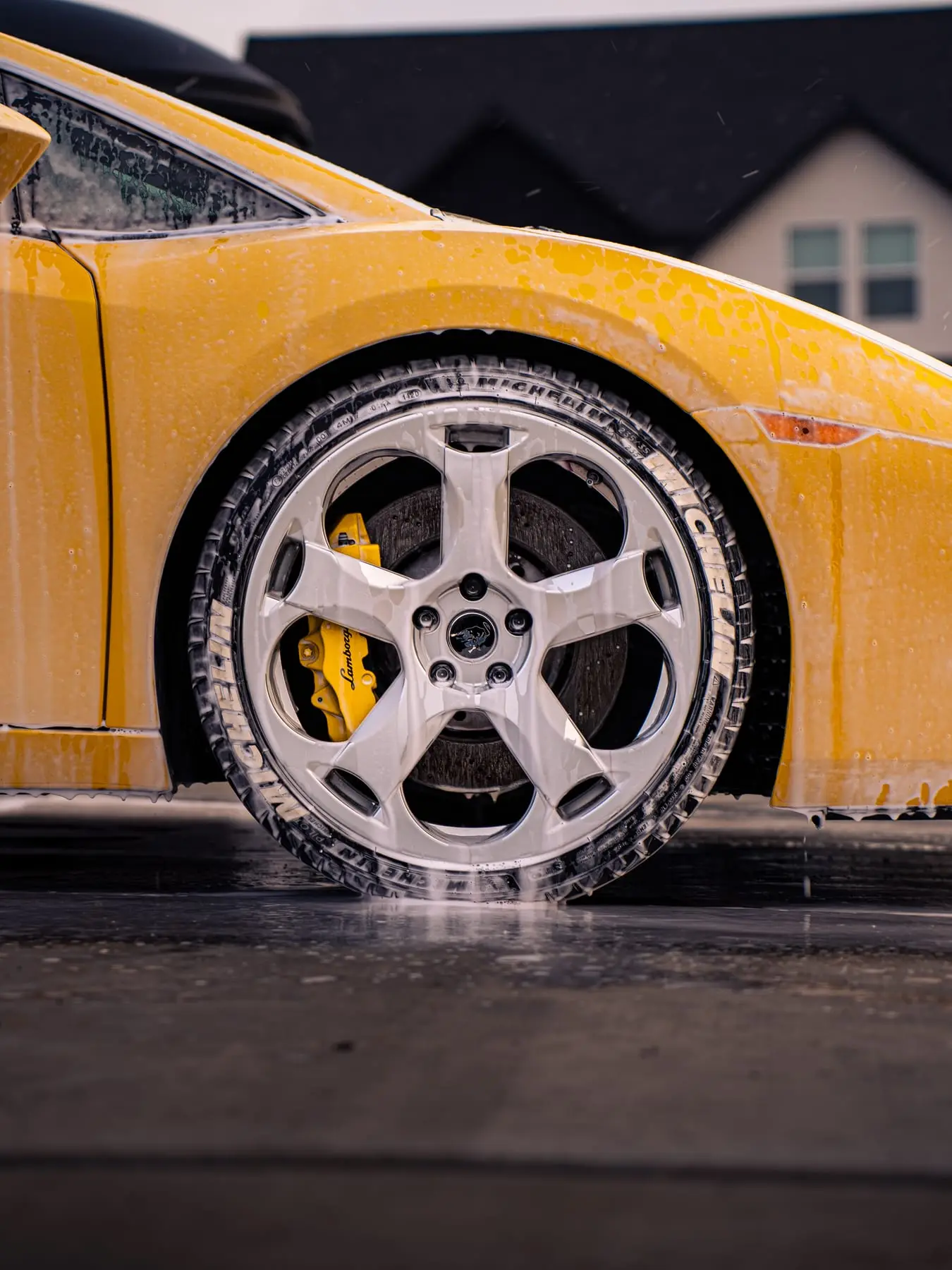 Suds running down the wheel and tire of a yellow Lamborghini Gallardo