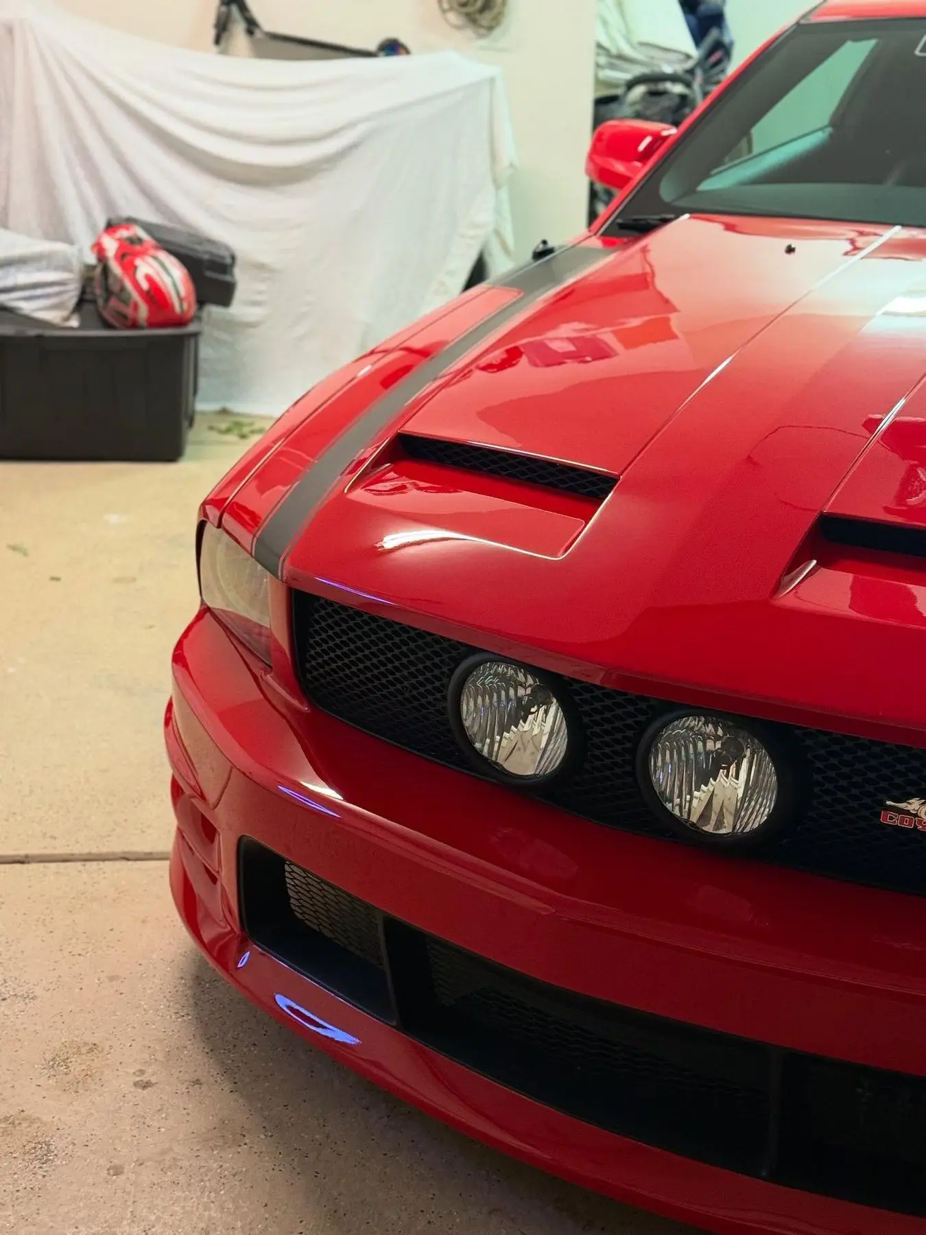 The nose of a red Mustang GT with black stripes