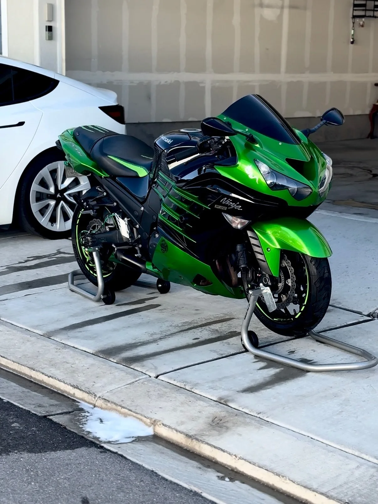 A bright green Kawasaki Ninja ZX-14 parked by a garage