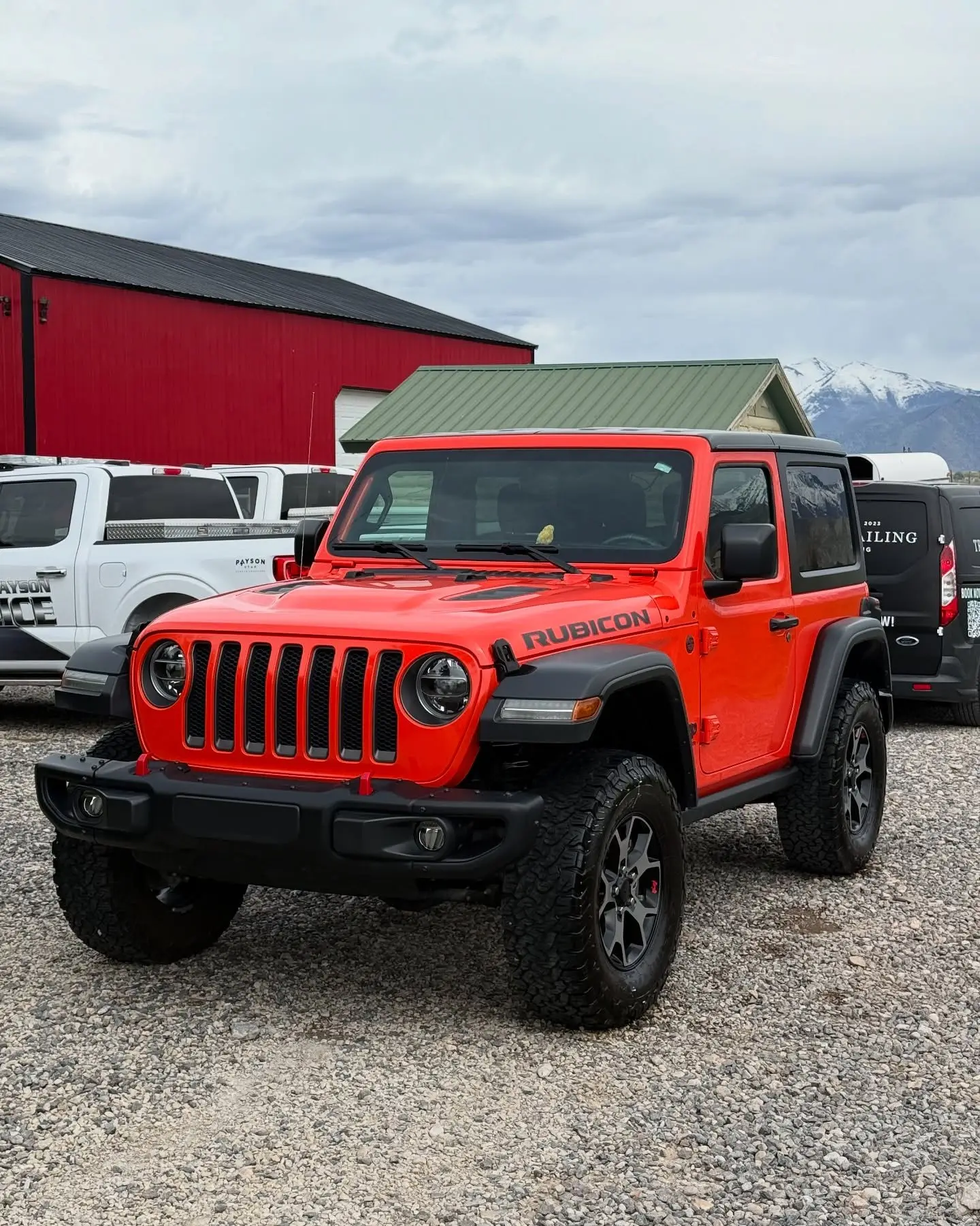 A red Jeep Wrangler Rubicon on a gravel lot