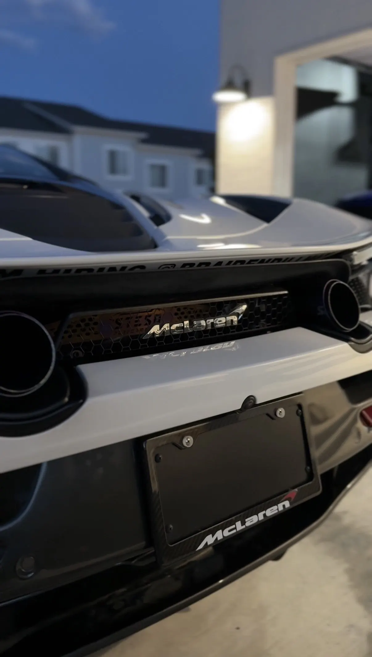 The rear panel and badge of a white McLaren up close at night