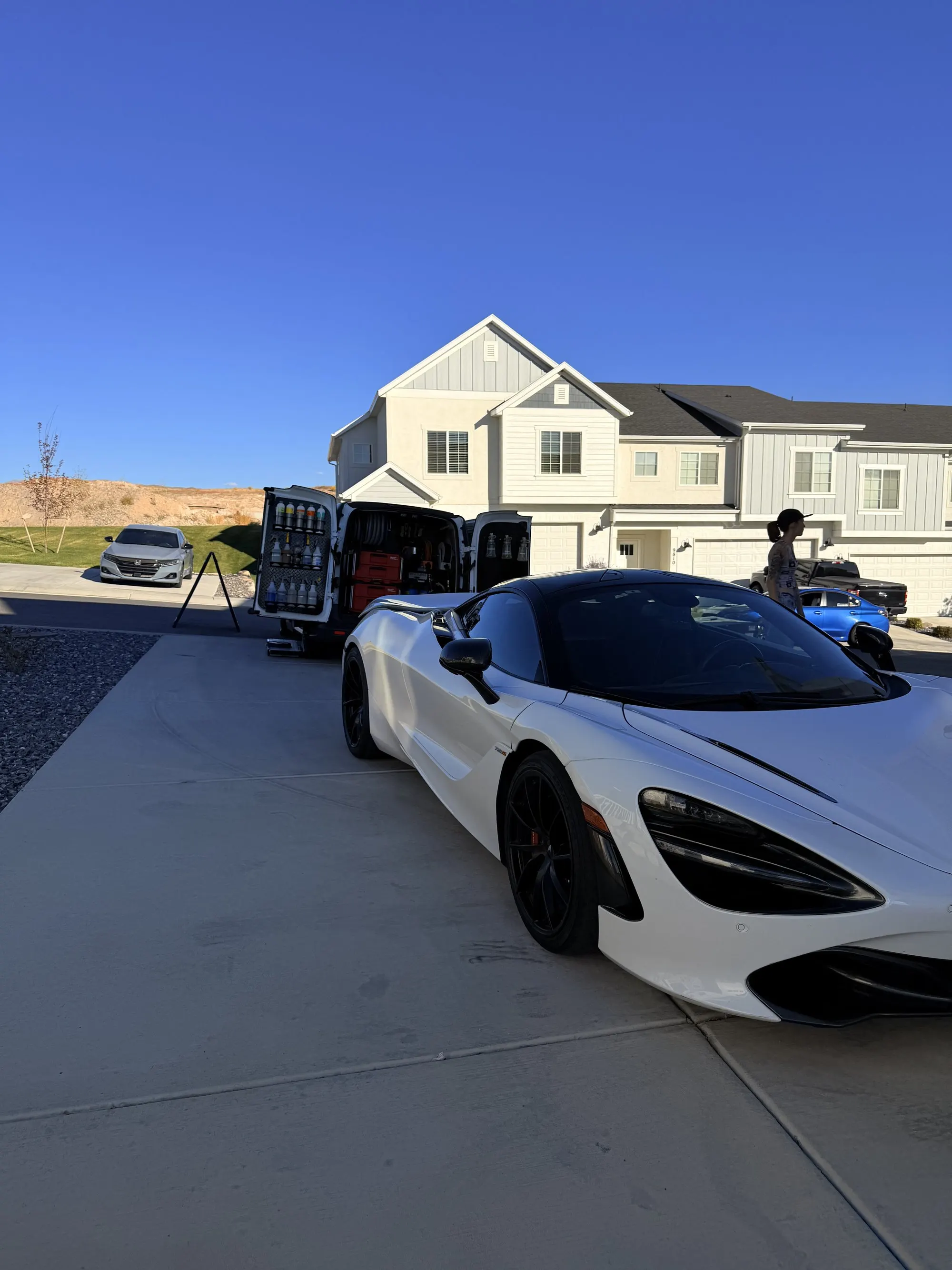 A white McLaren 720S washed and glossy in a client driveway