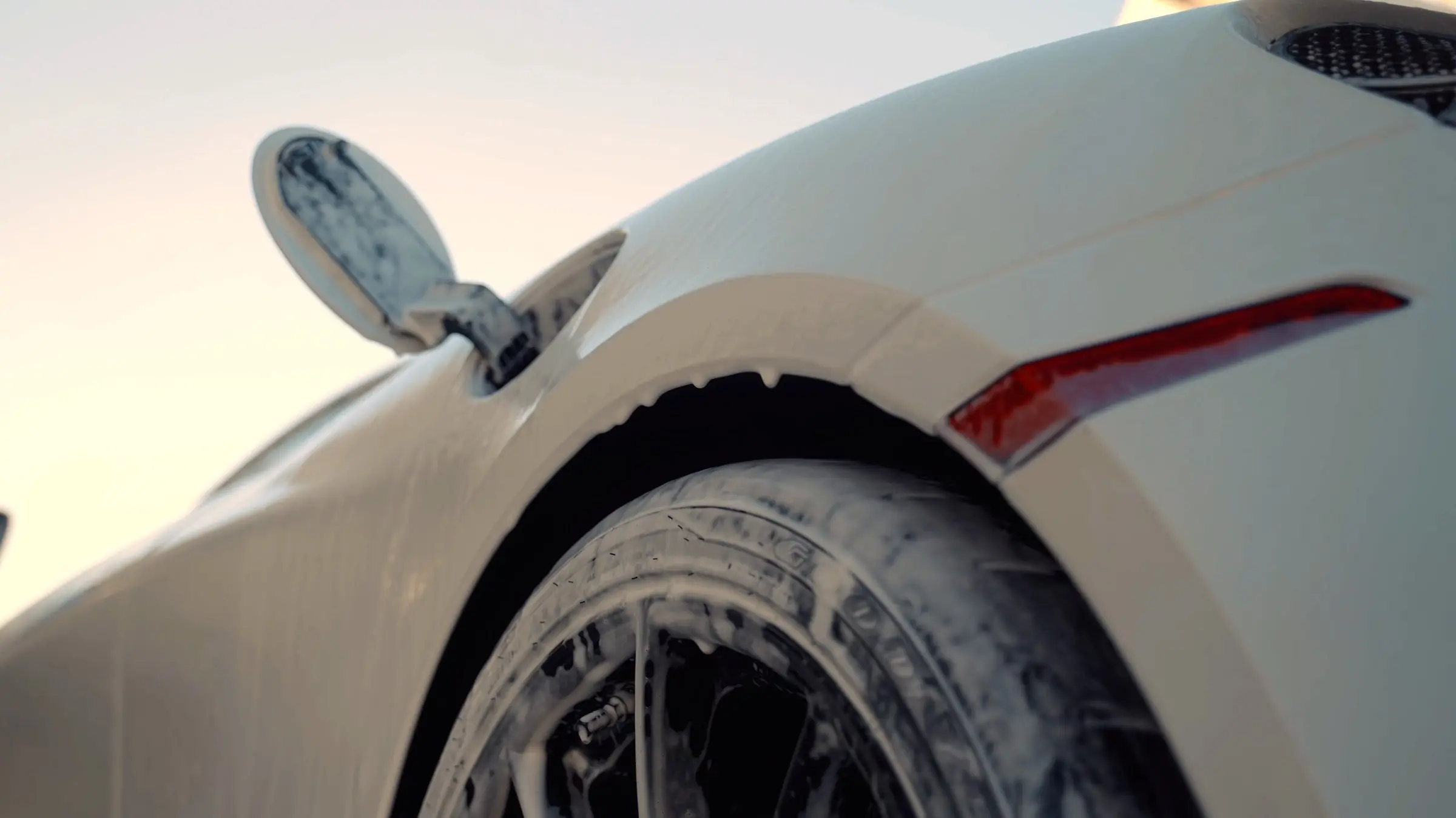 The popped mirror and foamed front wheel of a white McLaren 720S