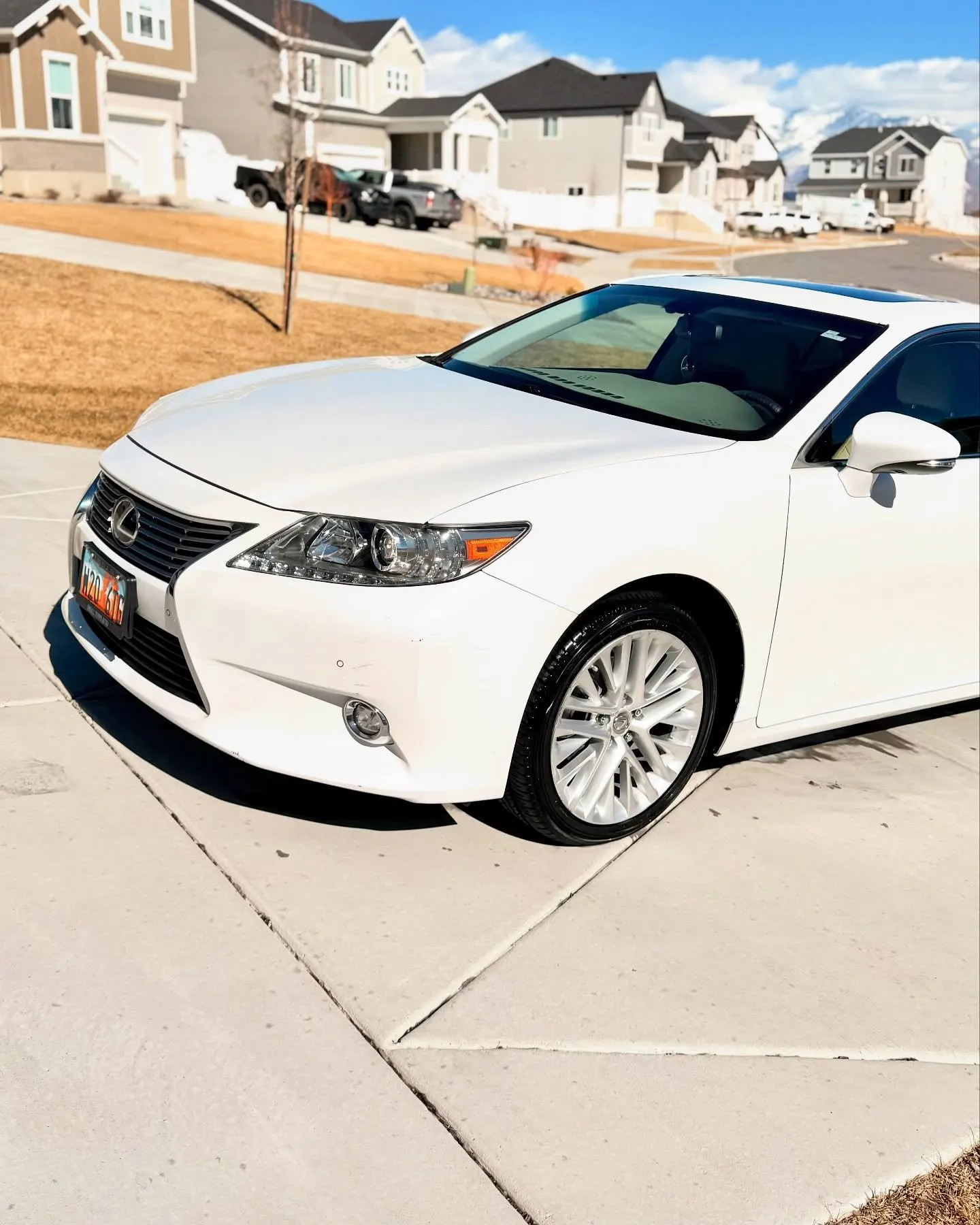 A white Lexus ES from the front three-quarter in a sunny driveway