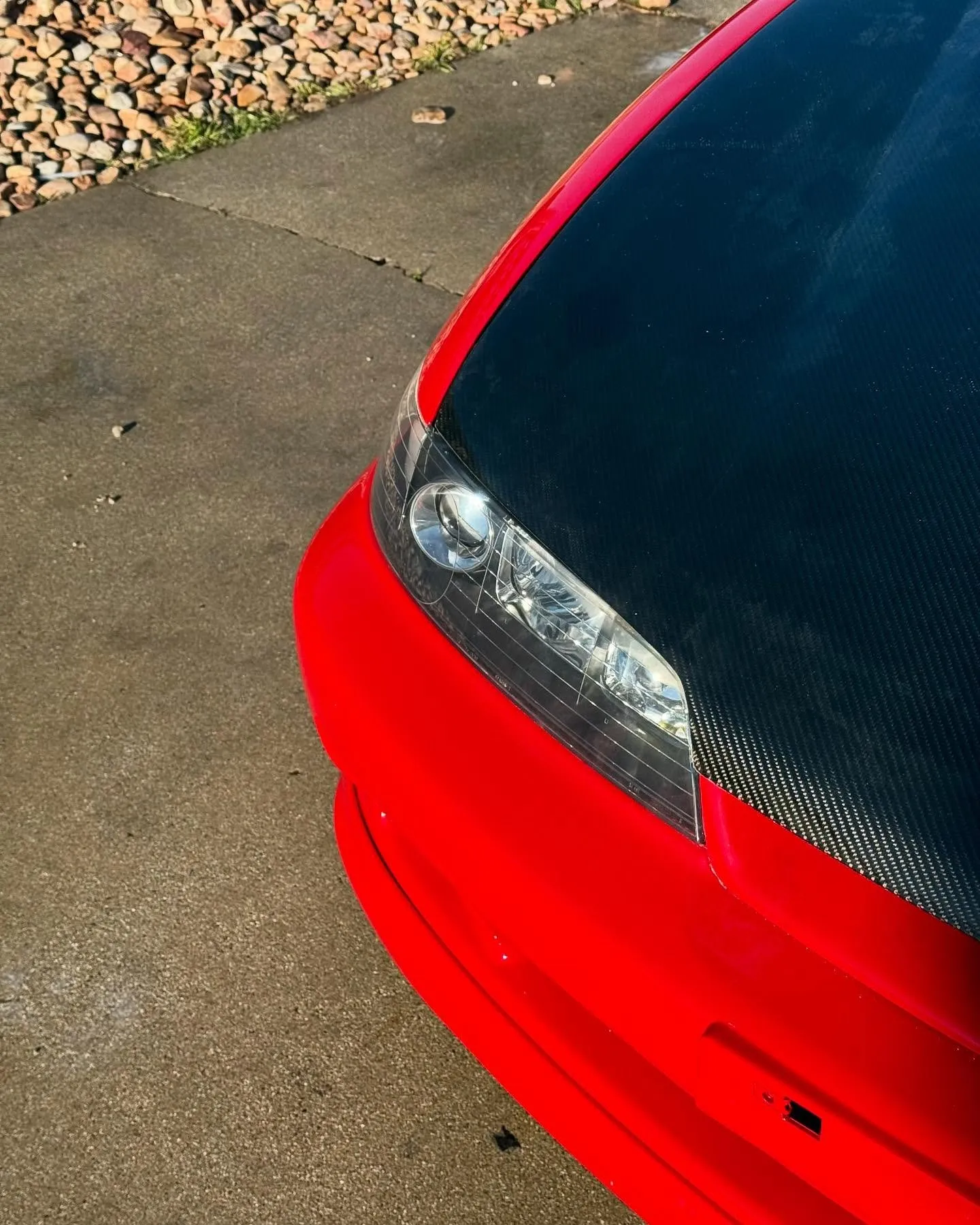 A red and carbon-black two-tone Acura Integra from the front quarter